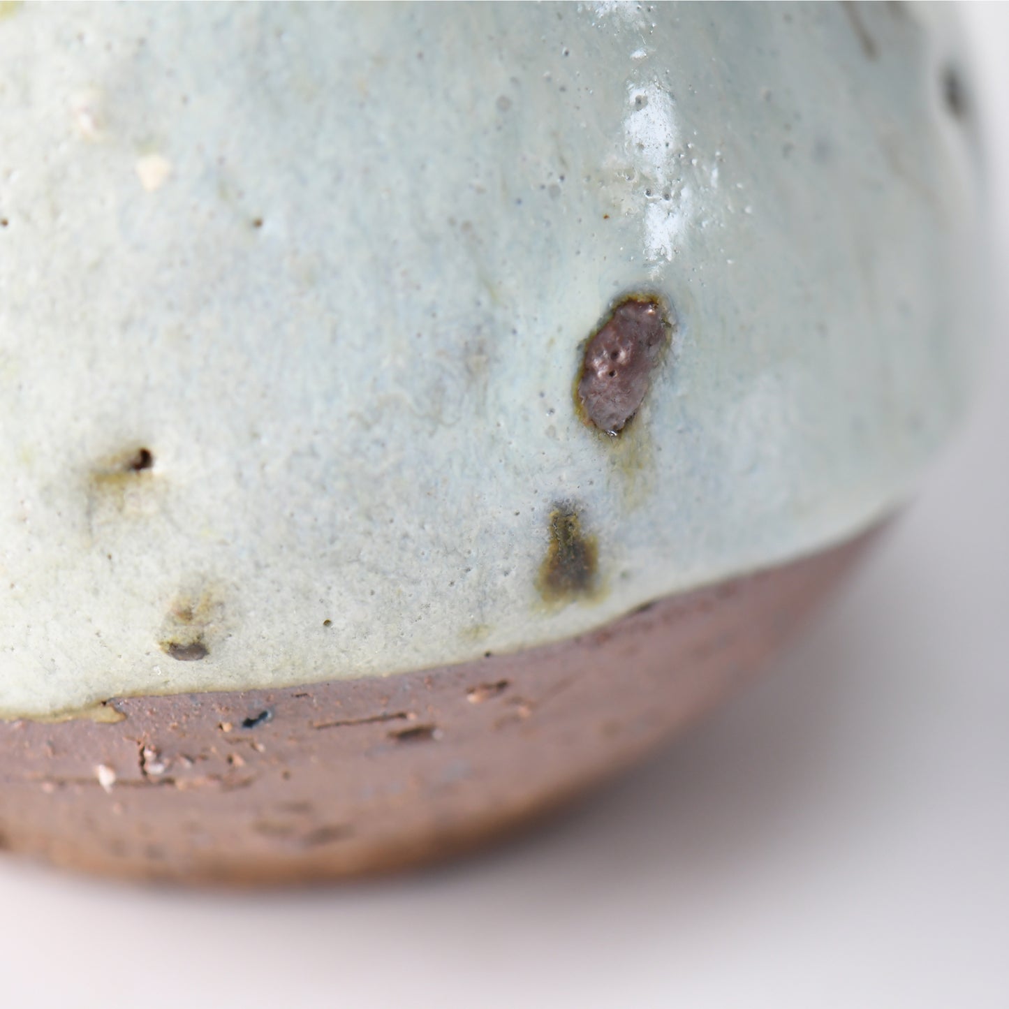 Detail of the “Hakuhō” sake carafe’s lower body, highlighting the transition from snowy glaze to raw clay base with natural kiln marks.