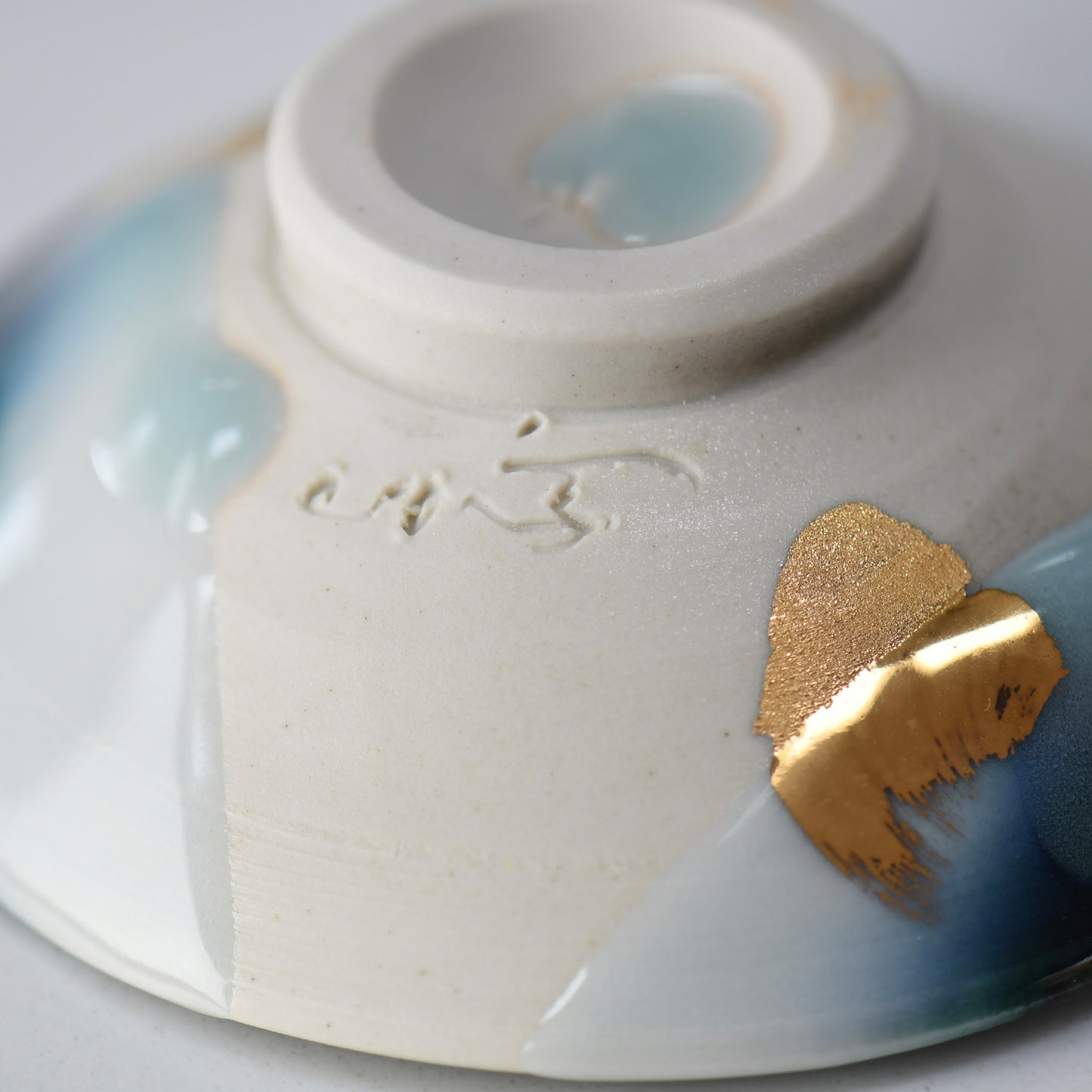 Underside of the gold guinomi showing Yoshu Takenishi’s impressed signature and gold detail.