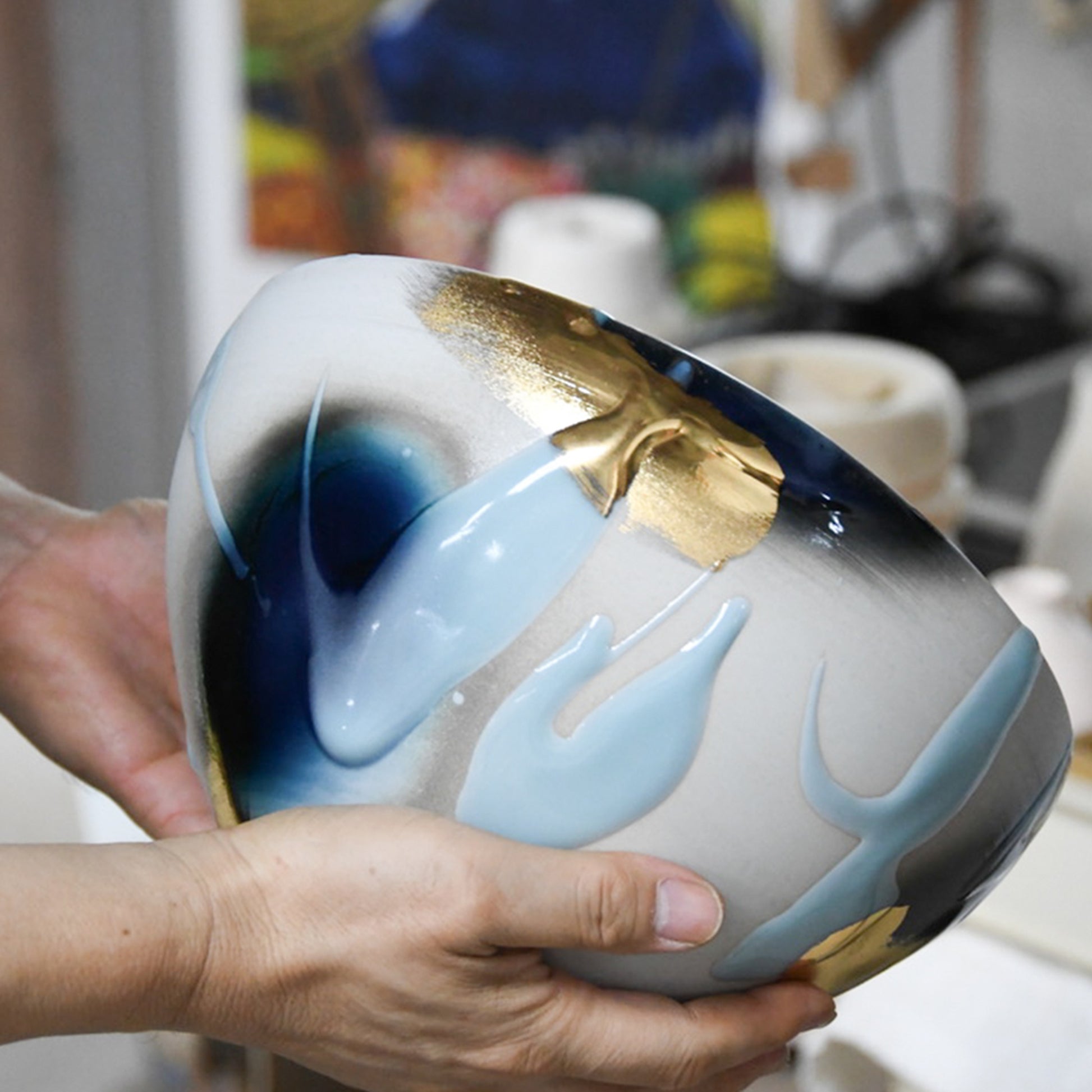 Yoshu Takenishi holding his Kage Ao ceramic bowl, highlighting hand-applied gold and celadon glazes.