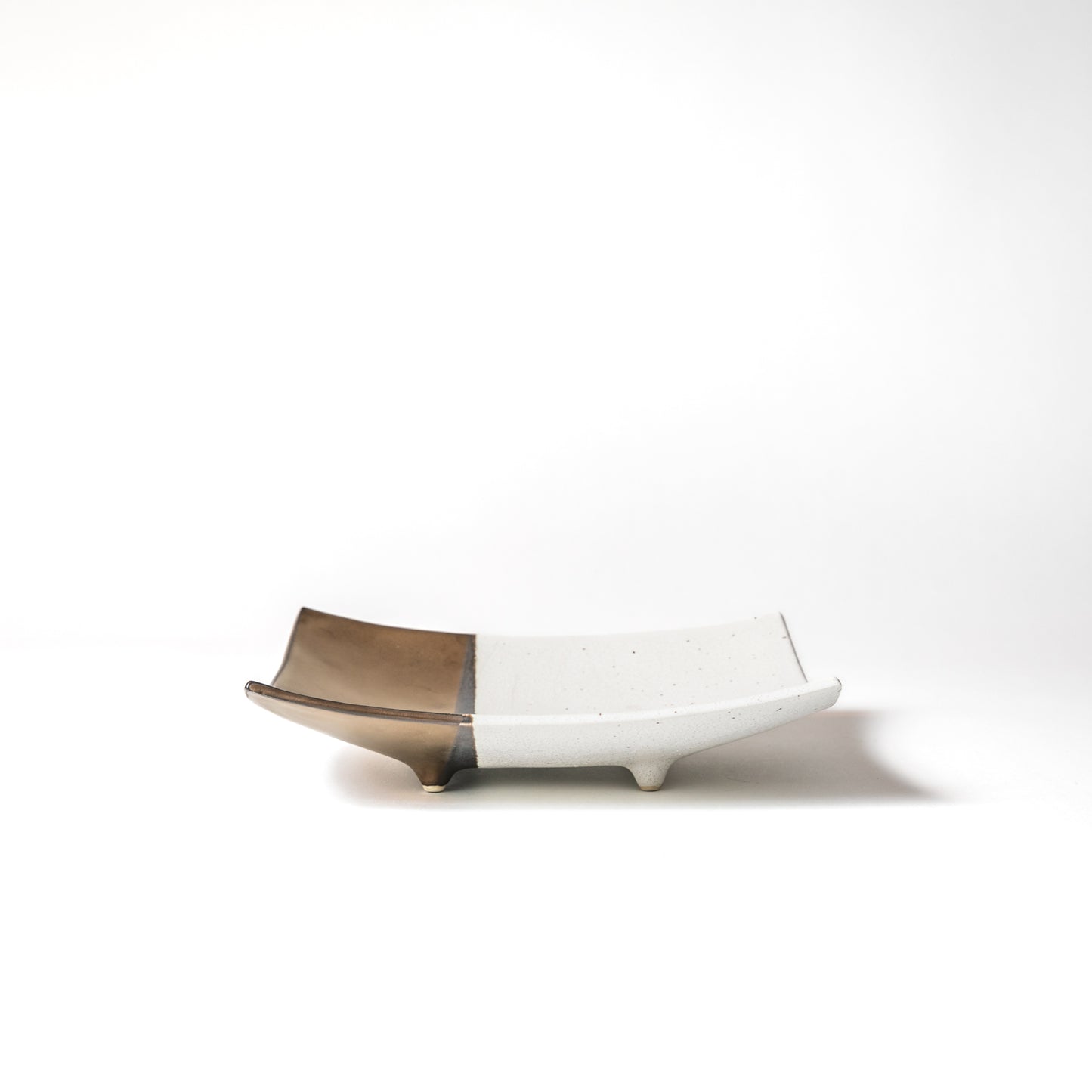 Side view of the white and gold footed square plate. It is gently curved, creating an elegant atmosphere.