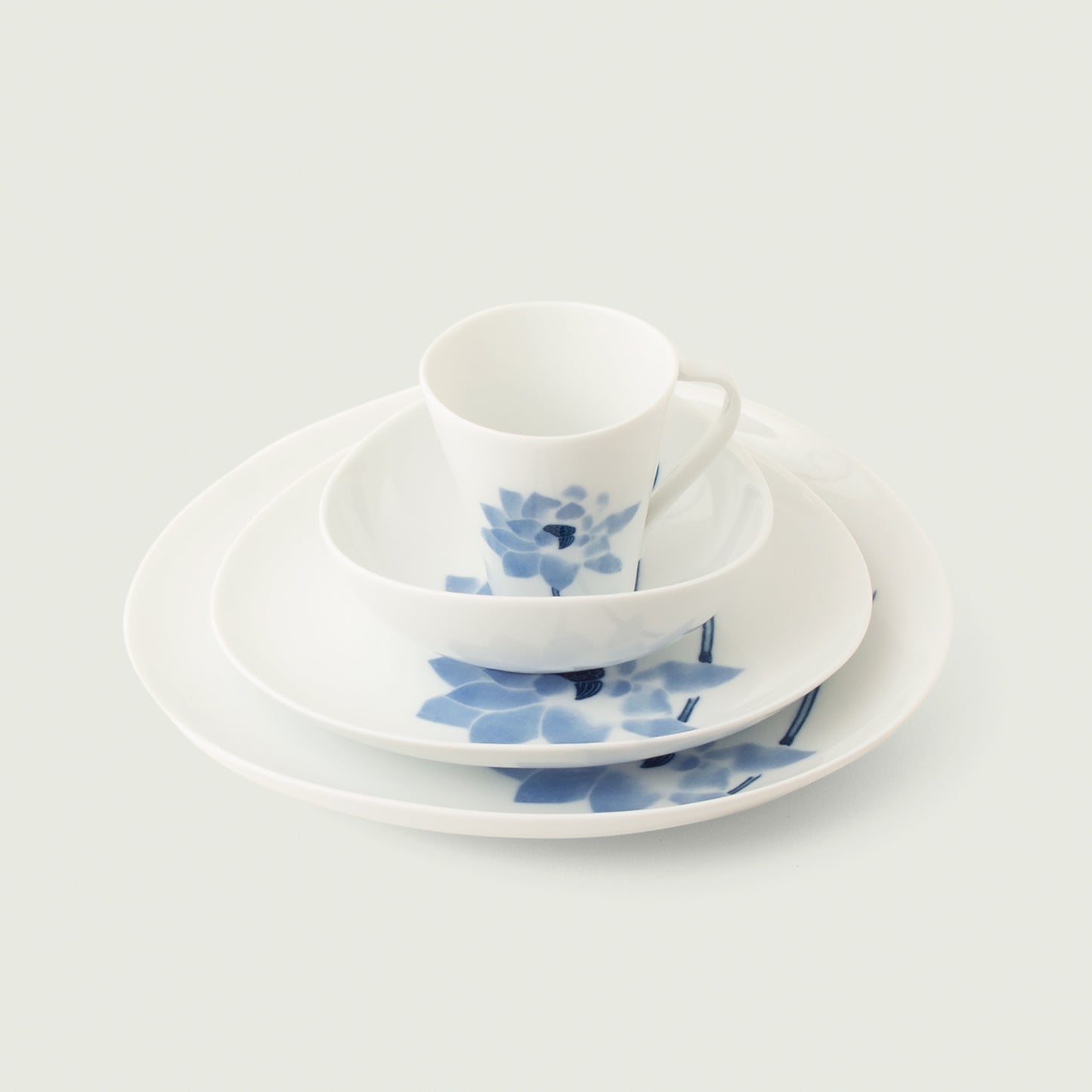 Hasu Japanese 4-piece dinnerware set - cup, bowl, salad, dinner plate. Features a blue lotus on a glossy white background.