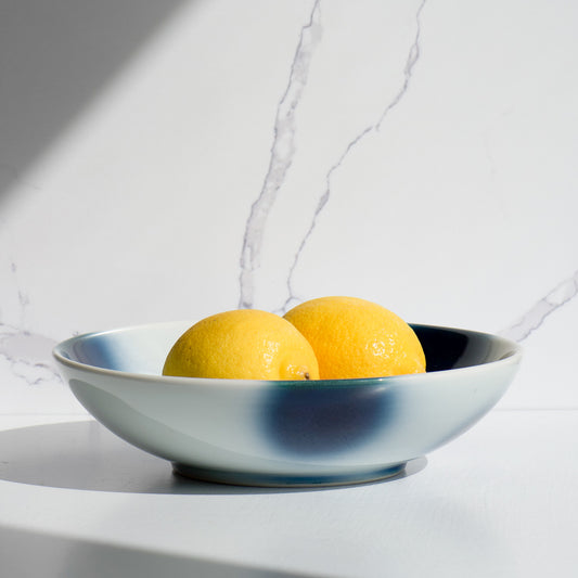 Mizu-oto pasta bowl styled with lemons under natural light on a marble background.