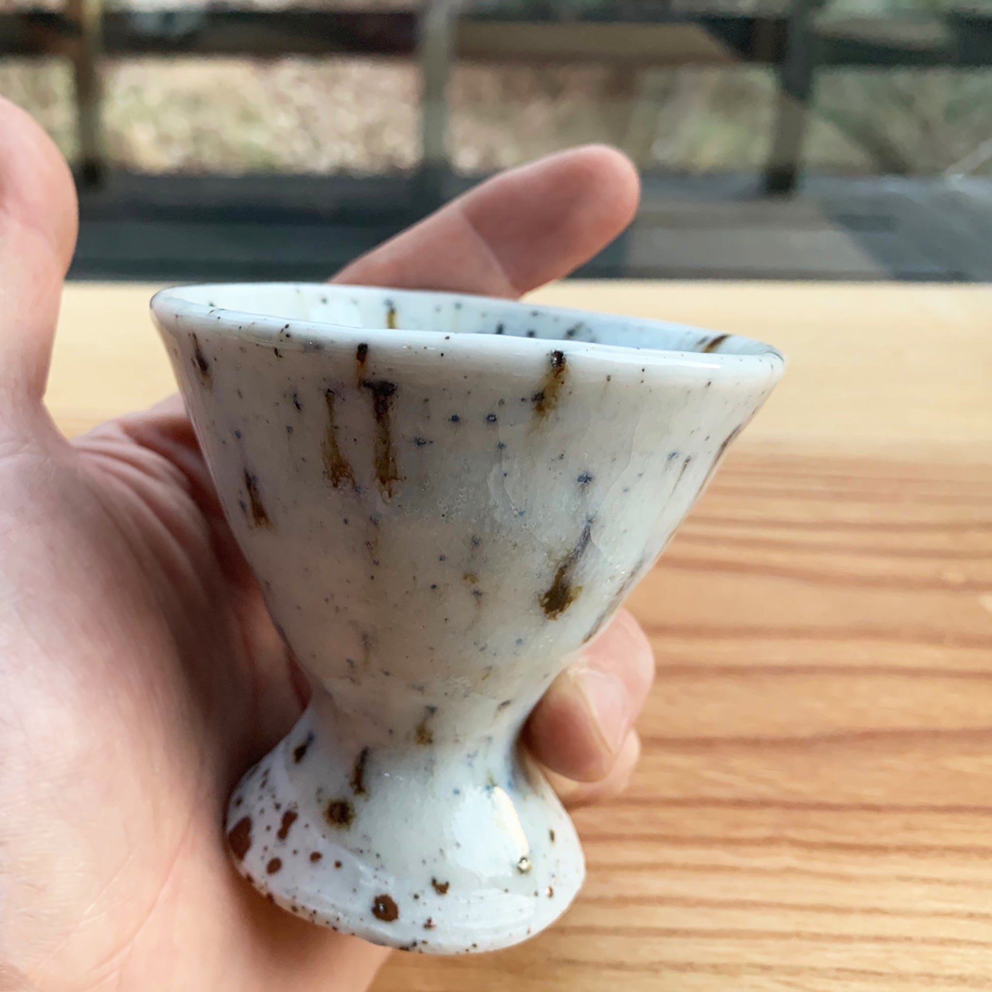 Kondo is holding the cup at his back yard. The cup looks so beautiful with wood table.