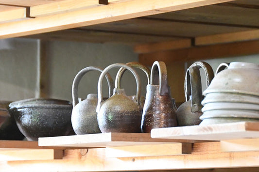 Bizen pottery vessels displayed on wooden shelves in Masato Miura’s studio
