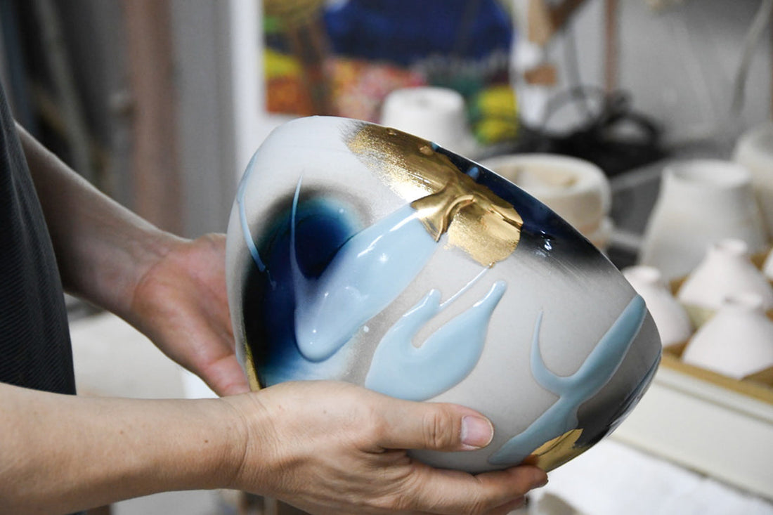 Yoshito Takenishi holding a handmade ceramic vessel with flowing glaze and gold detail