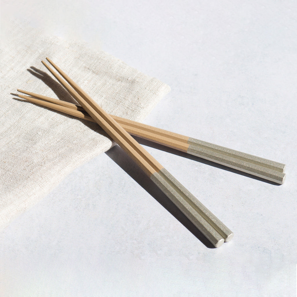 A pair of handmade silver lacquered chopsticks from Japan resting on a napkin. Modern Japanese tableware. Elegance and luxury.