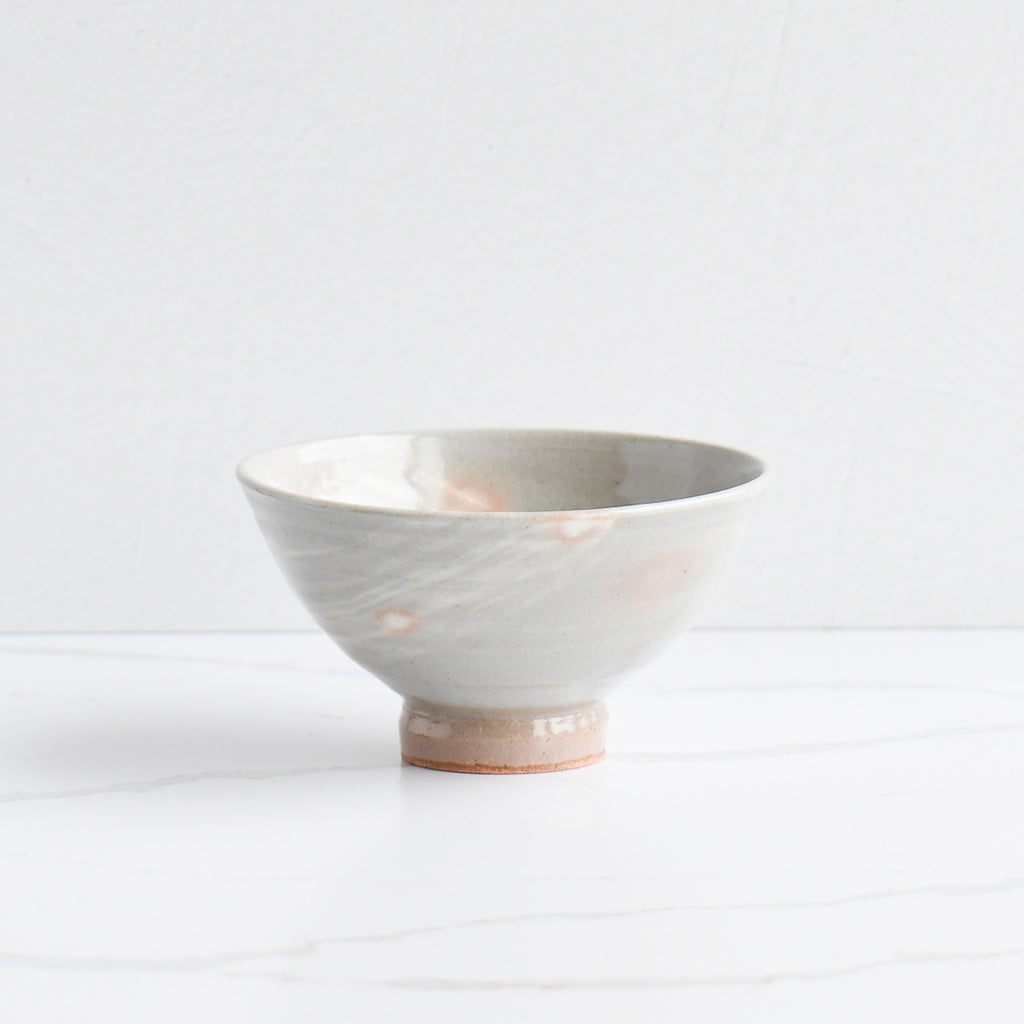 An artisanal Mashiko bowl with a soft gray glaze, subtle orange accents, and an unglazed, textured base. WAZA Tokyo exclusive Japanese tableware available in the US.