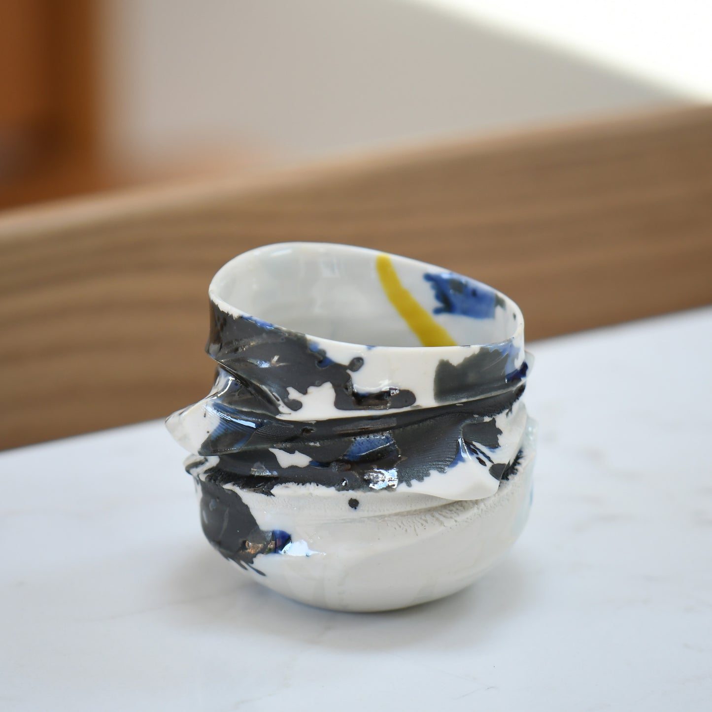 Ensai guinomi #3 on the table – flame-toned handmade sake cup with sculptural spiral. Bold black design with the hint of blue and yellow.