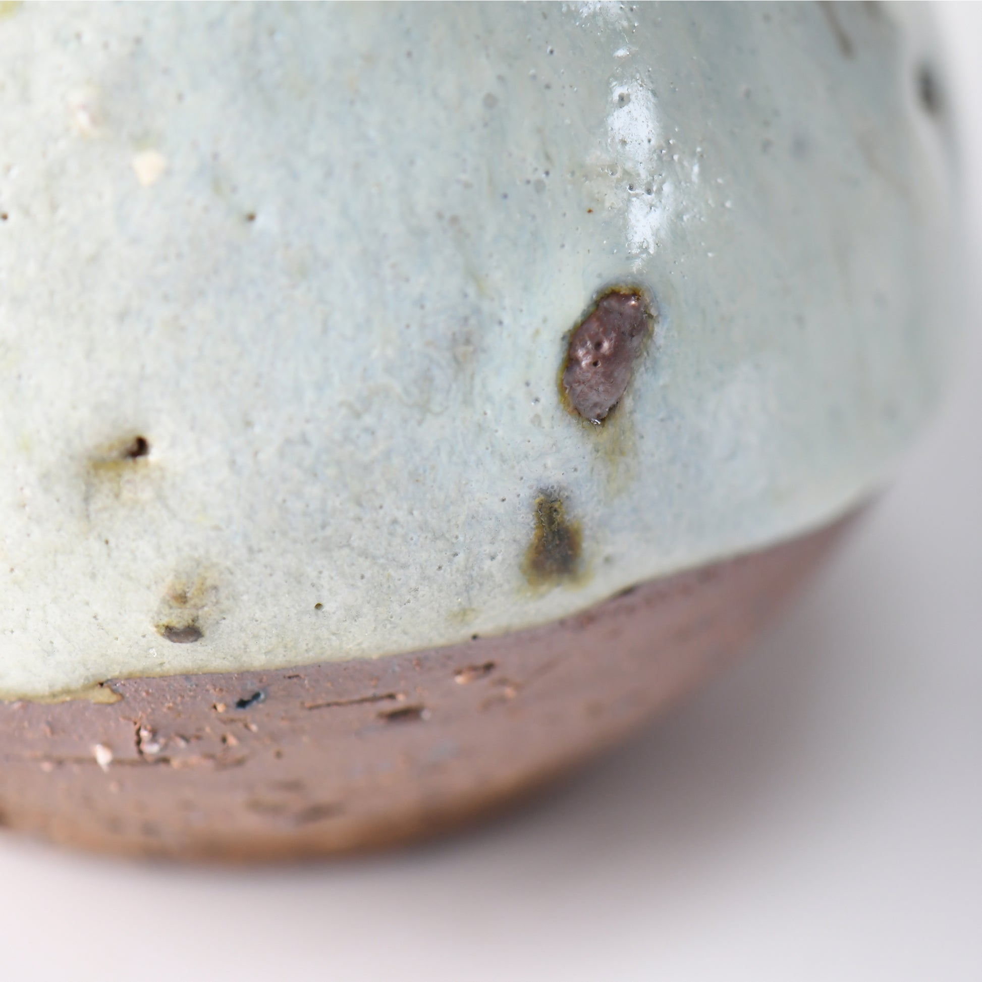 Detail of the “Hakuhō” sake carafe’s lower body, highlighting the transition from snowy glaze to raw clay base with natural kiln marks.