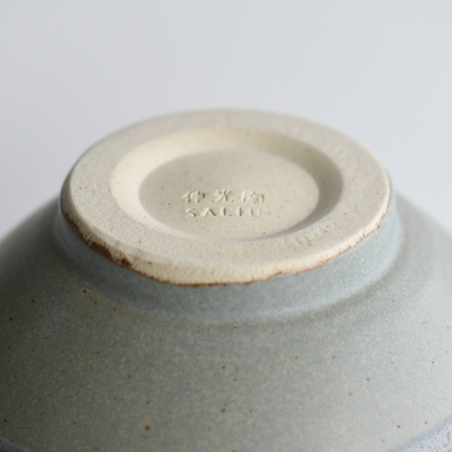 Underside of Yusui Stormy Moss matcha bowl with Shinko Kiln mark and unglazed clay foot ring