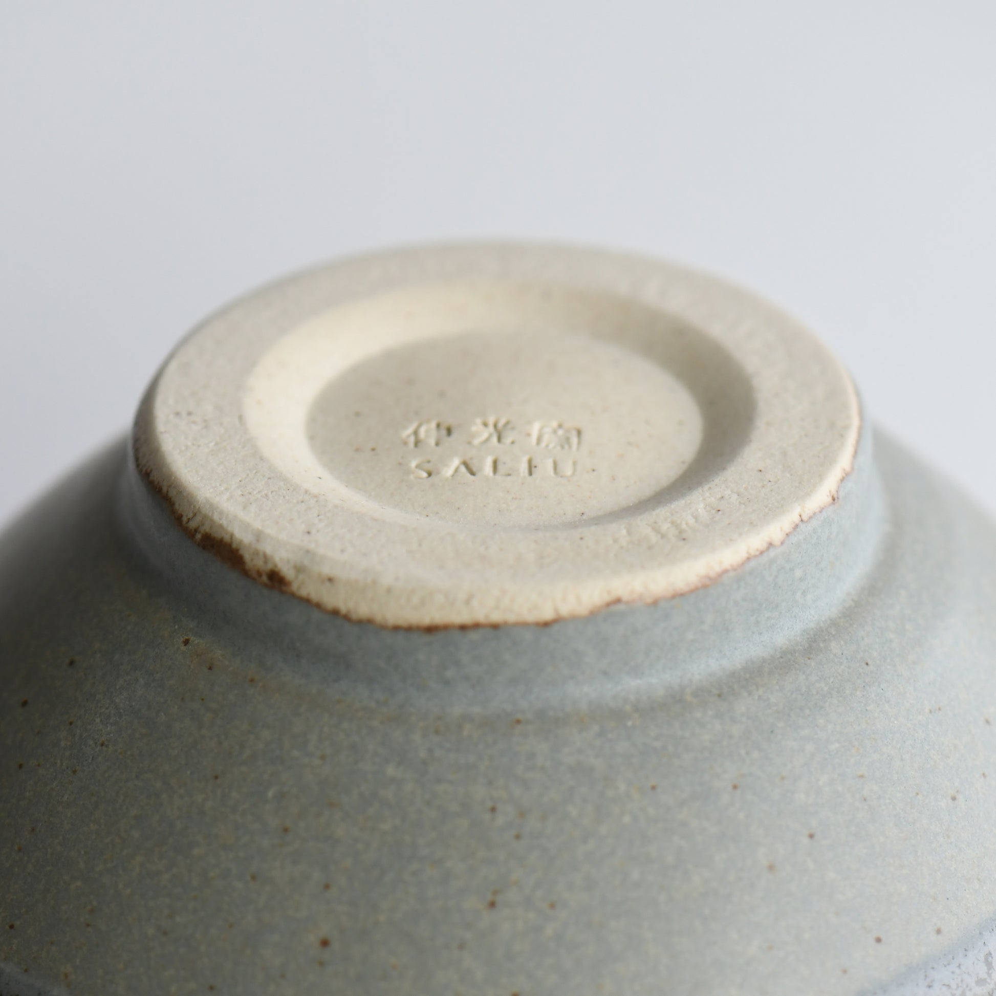 Underside of Yusui Stormy Moss matcha bowl with Shinko Kiln mark and unglazed clay foot ring