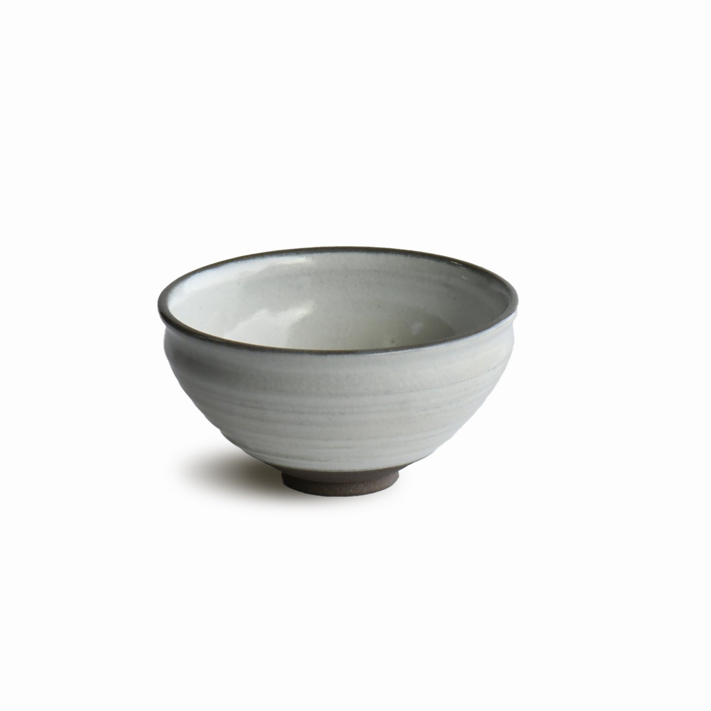 Angled view of Hakuei chawan by Shinko Kiln highlighting curved form and subtle shadow beneath the rim