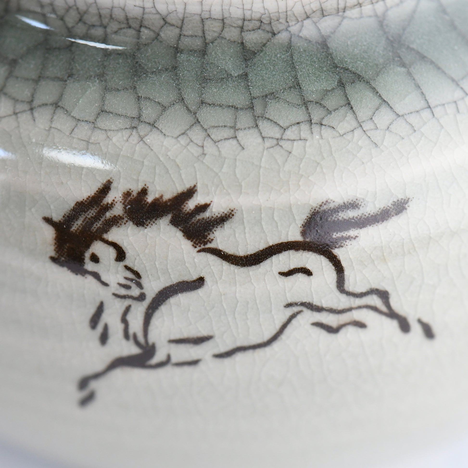 Close-up of hand-painted 左馬 horse design on celadon teapot, symbol of good fortune.