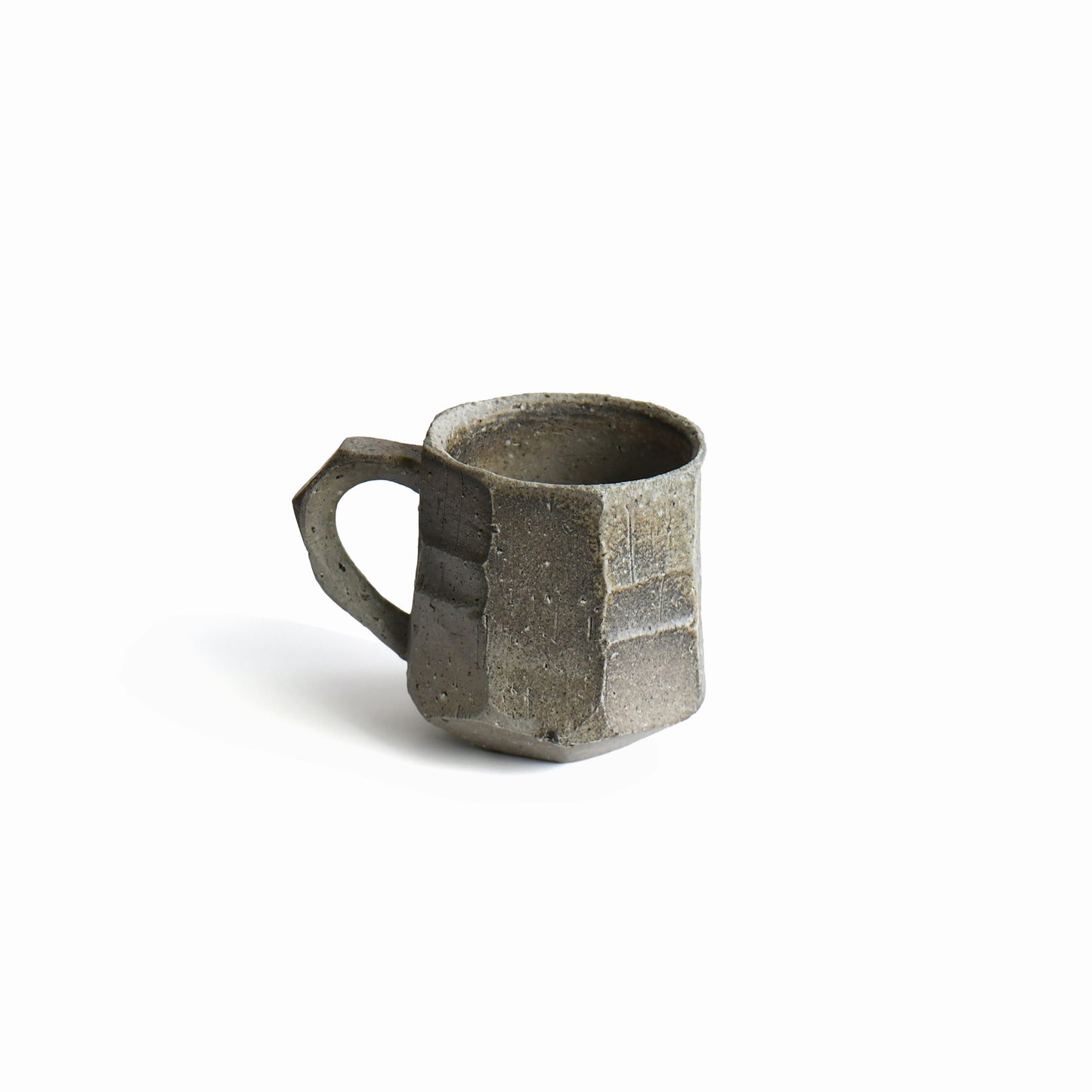 Back view of Seihitsu Sueki Mug Medium #2 showing sculpted planes, iron-speckled clay texture, and architectural silhouette.