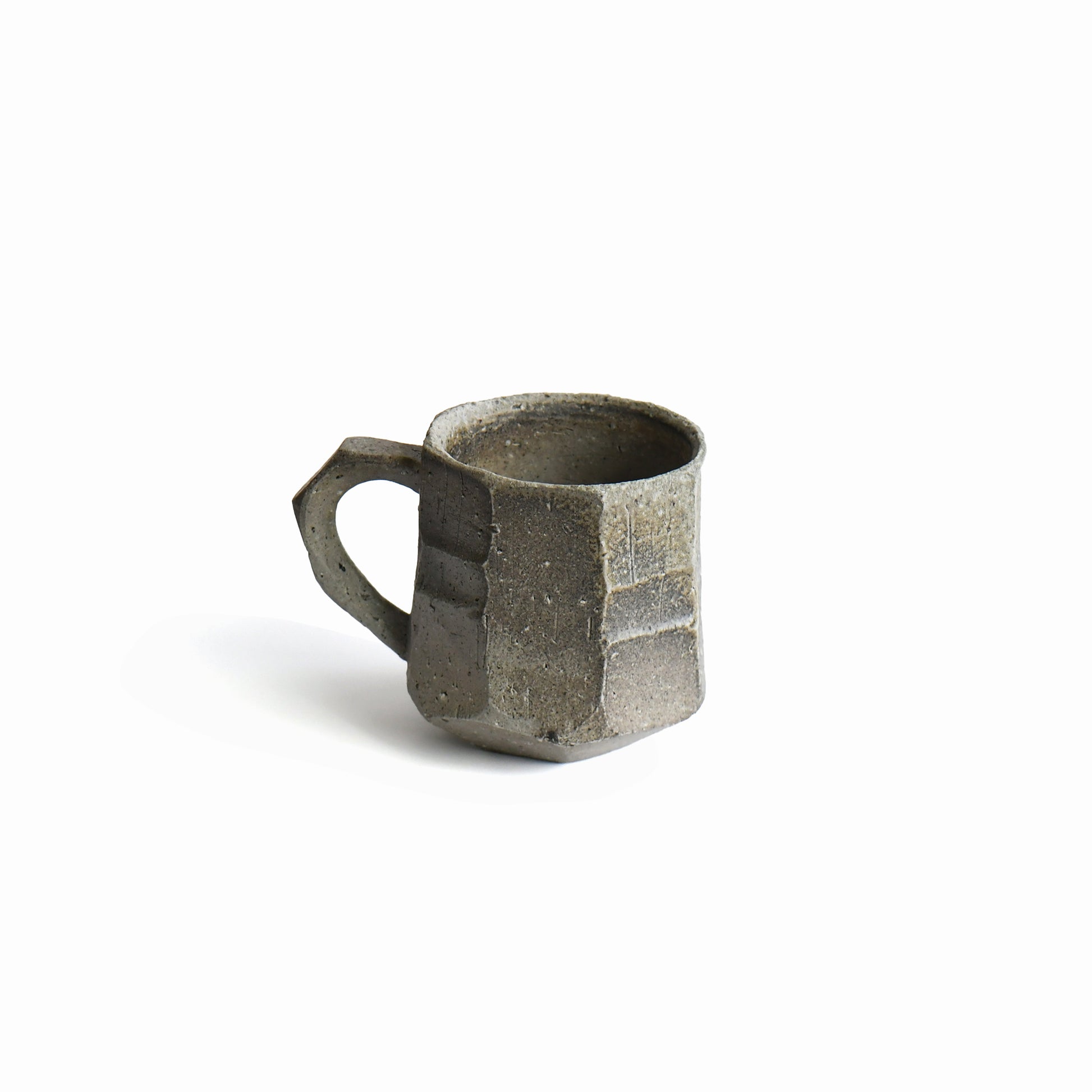 Back view of Seihitsu Sueki Mug Medium #2 showing sculpted planes, iron-speckled clay texture, and architectural silhouette.
