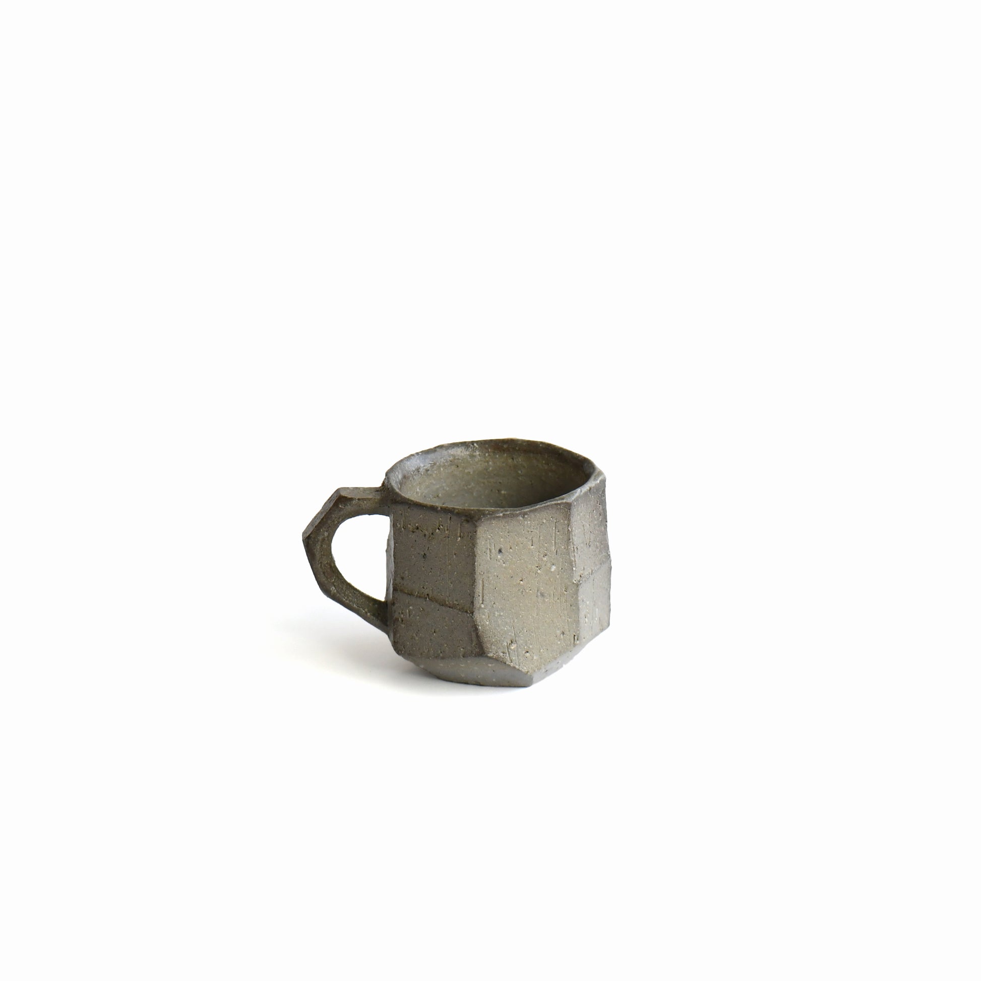 Back view of Seihitsu Sueki Mug Small #2 showing sculpted planes, darker kiln-fired variation, and iron-speckled clay texture.
