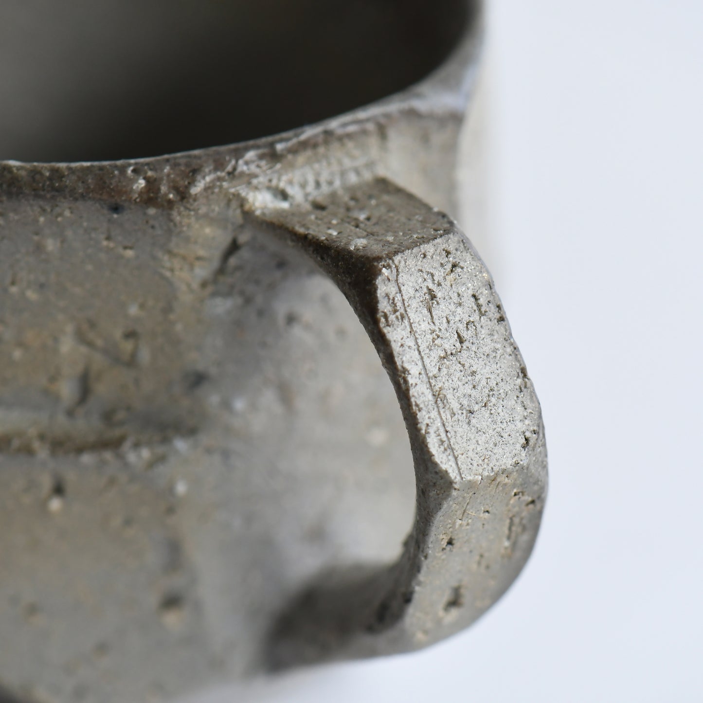 Close-up of angular handle and textured stoneware surface on Seihitsu Sueki Mug Small #2 highlighting carved edges and natural firing marks.