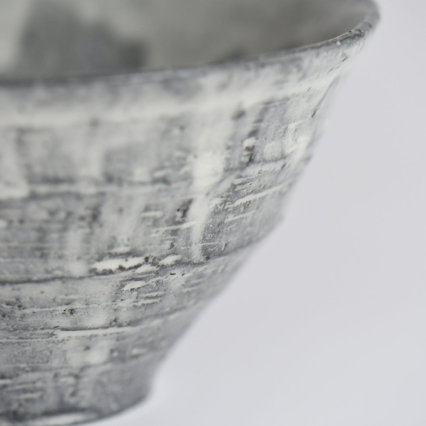 Close-up of the charcoal-gray textured surface and layered white glaze of the handmade Sumine Rice Bowl.