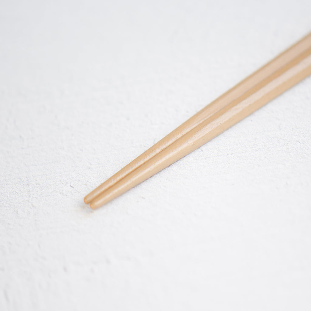 A close-up image of the rounded tops of natural wood chopsticks, designed for easy grip when picking up food. Handmade. Made in Japan. 