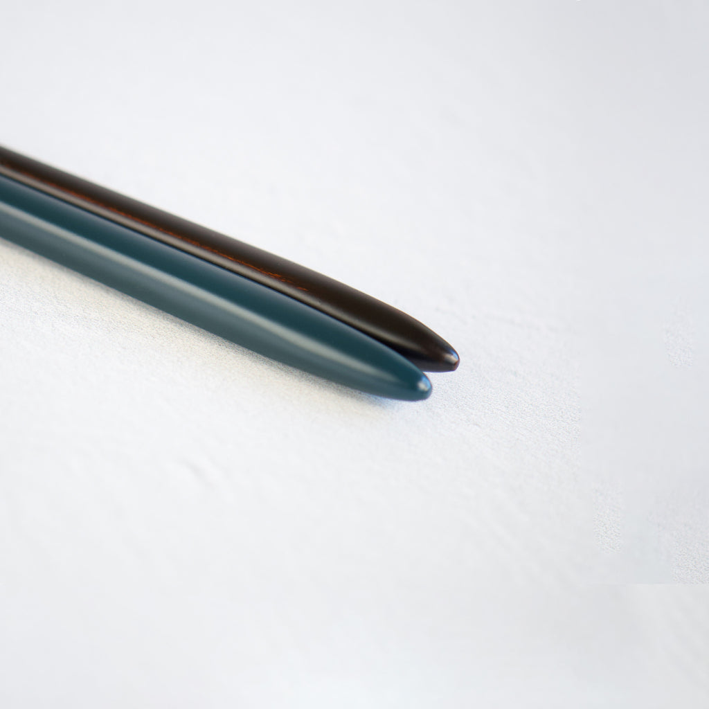 A close-up image of the elegantly divided tops of the chopsticks, featuring a half-and-half rouge and black lacquered finish, showcasing a unique and contemporary design.