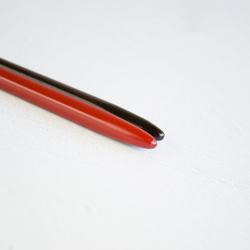 A close-up image of the contrasting tops of the chopsticks, with a smooth and glossy rouge and black lacquered finish, providing a comfortable grip and a stylish flair to your dining experience.