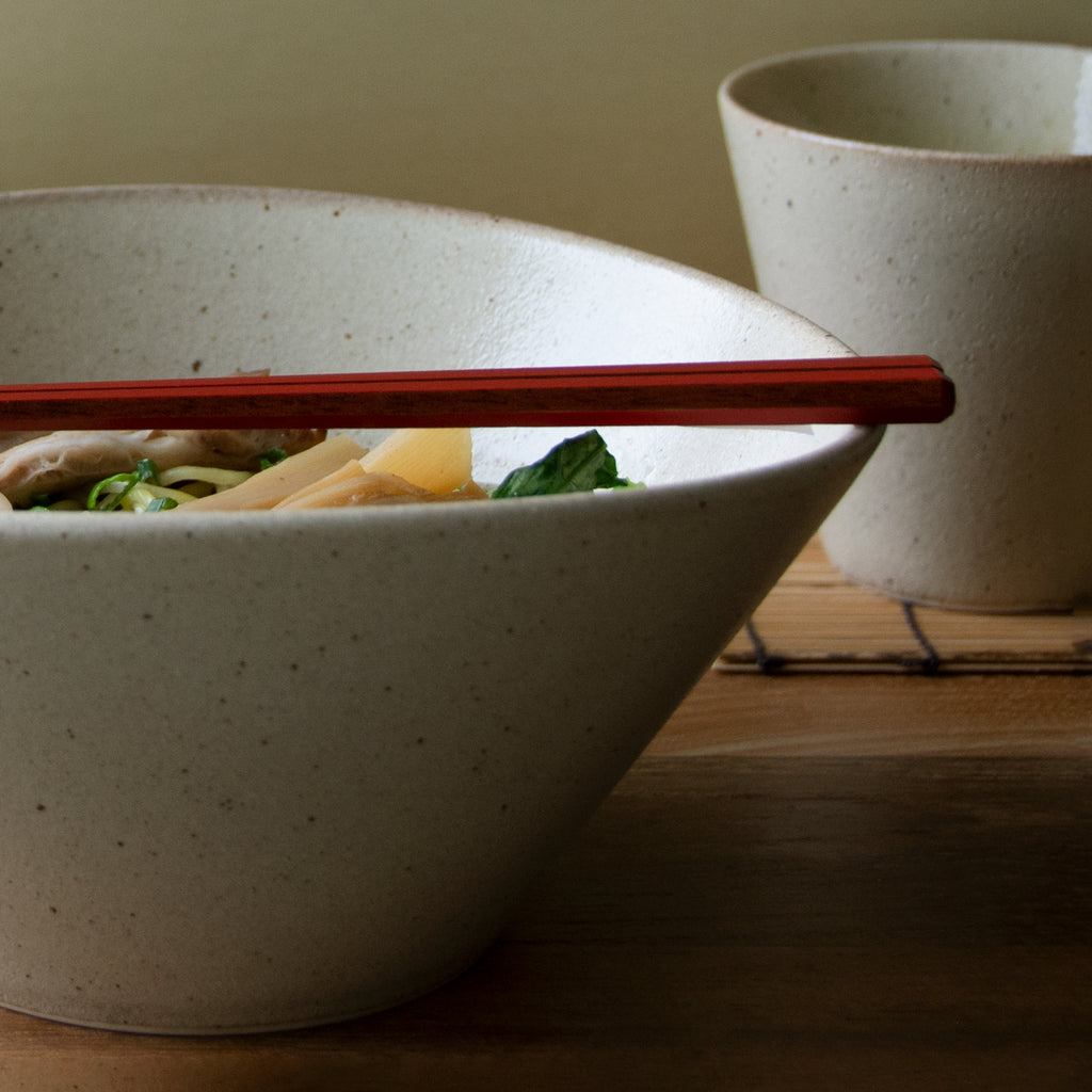 Tapered ramen bowl with undulating rim with matching tapered tea cup in background