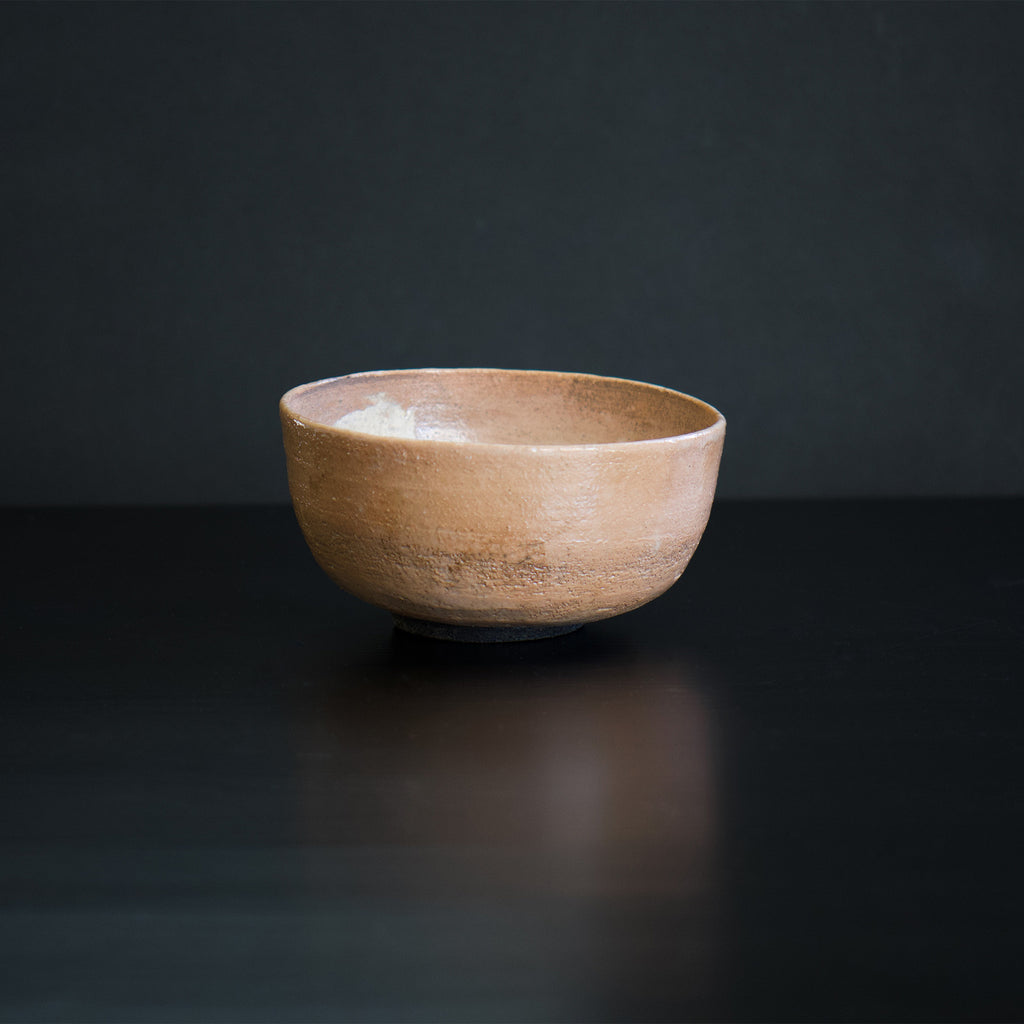 This is a serene pink matcha tea bowl, called "chawan", which is a type of unique tableware. It was carefully made by a Japanese artist who is currently based in France. The surface of the bowl retains the texture of the clay used to make it, which adds to its beauty. 