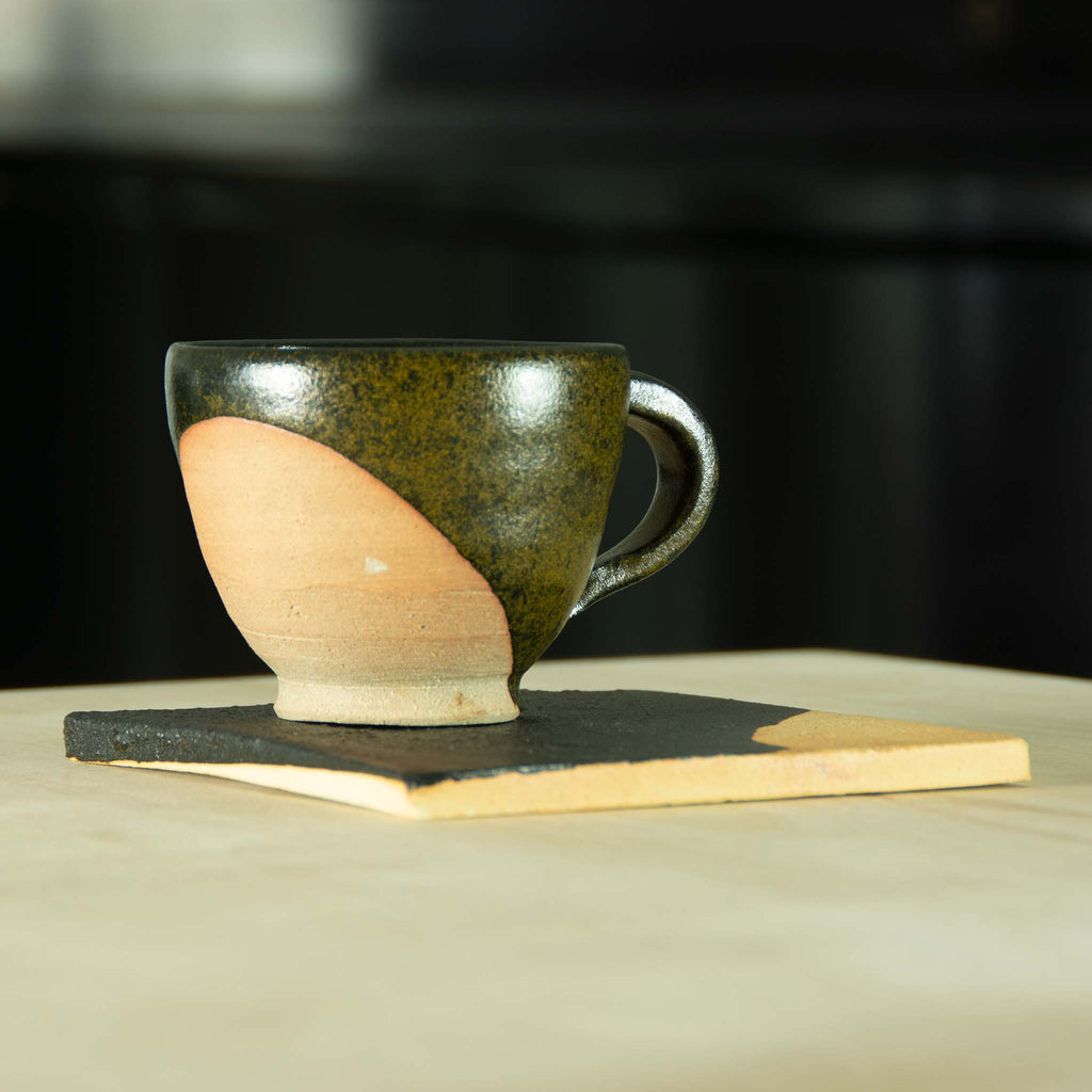 Coffee/tea cup partially glazed black and ochre with clay exposed as an elegant design motif