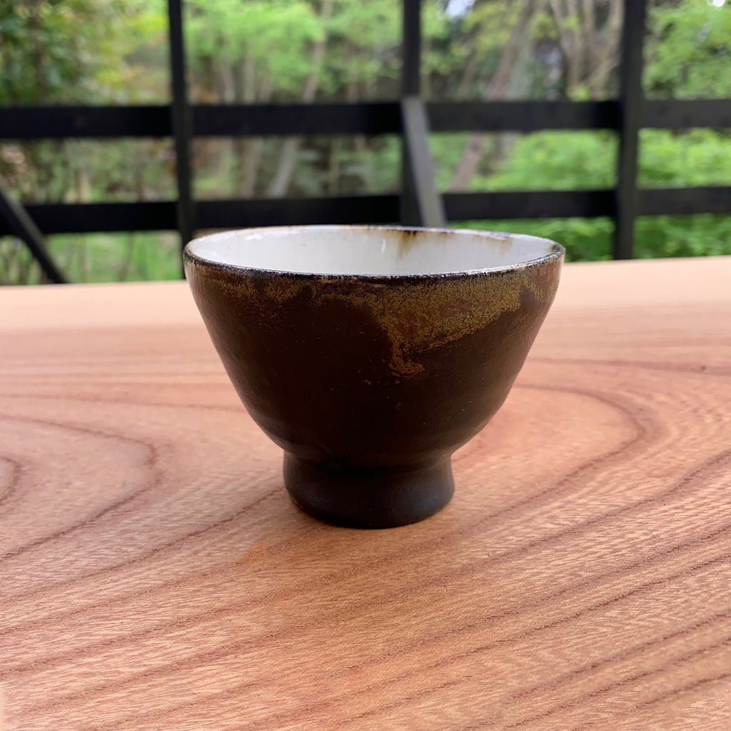 Side view of the cup. The cup is on the wooden table. Golden brown color is shown on the side. 