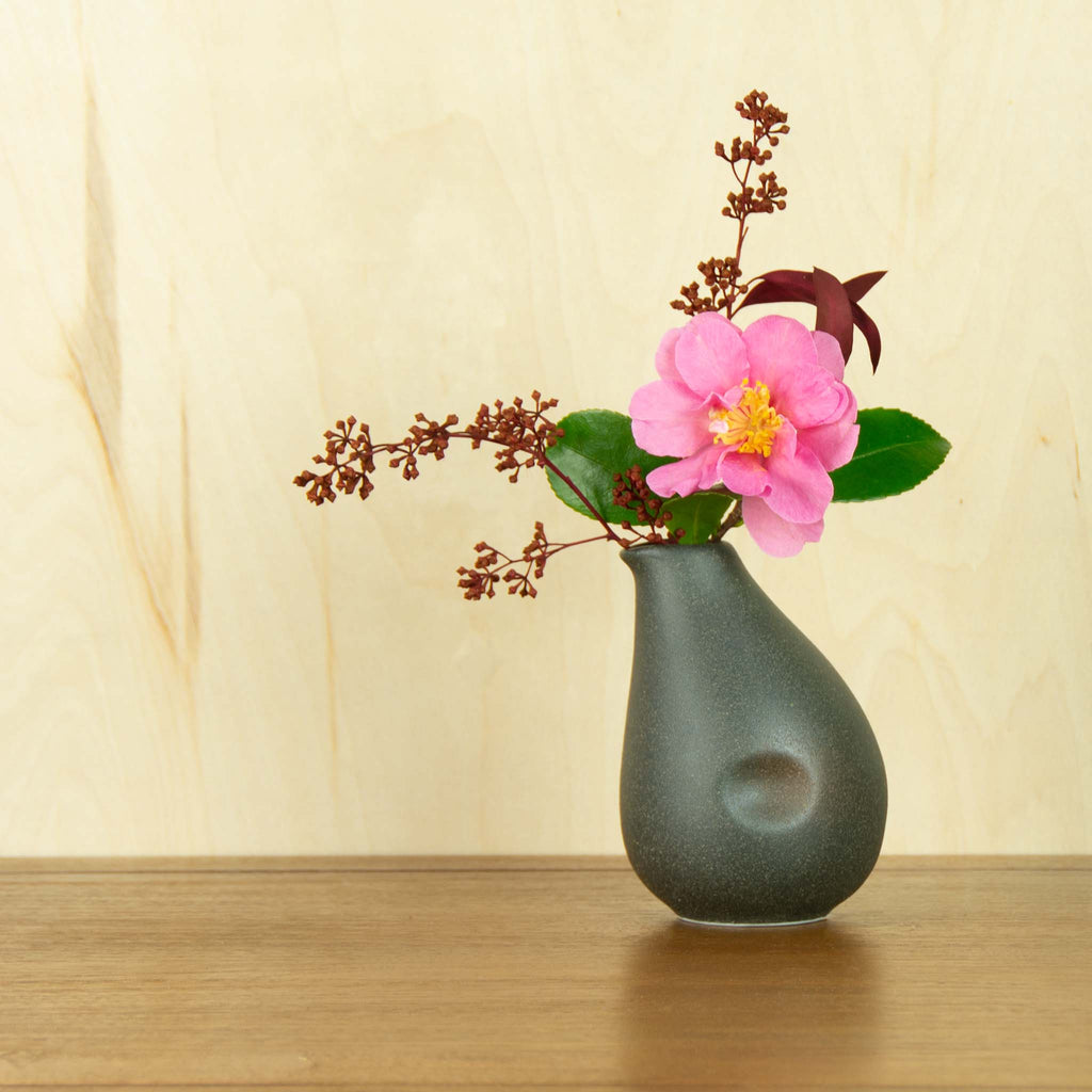 Speckled dark grey sake container vase with red eucalyptus combined with pink camelia