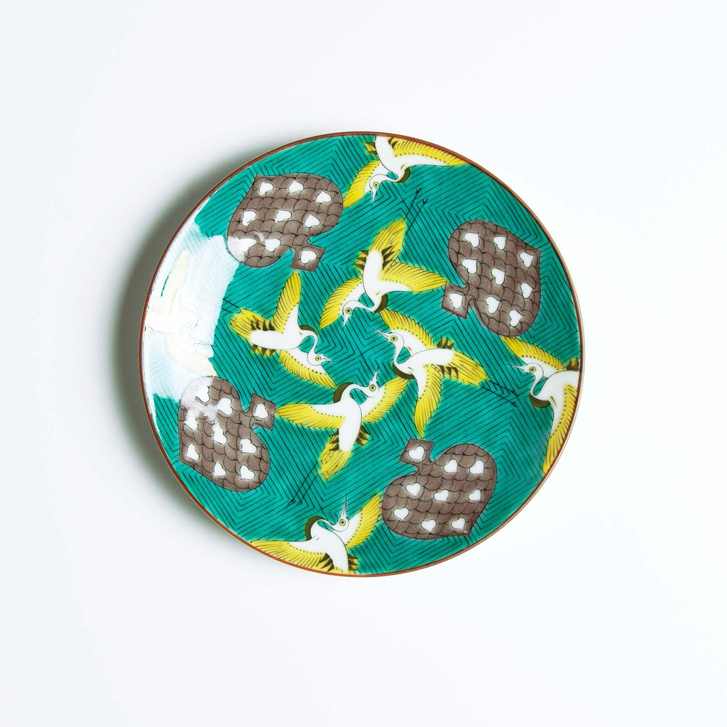 Round dish with yellow and white birds flying among spades rich green background
